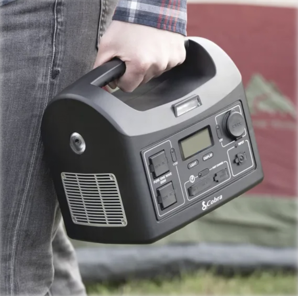 A portable power station with multiple outlets and a digital display, held by a person.