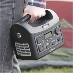 A portable power station with multiple outlets and a digital display, held by a person.