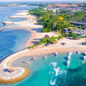 Aerial view of a tropical coastline with boats and a resort.