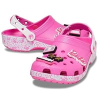 Pink clogs with a Barbie print, featuring a charm of the Barbie logo on the front and branded heel straps.