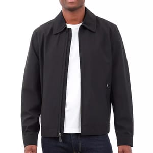 A person is wearing a black, lightweight jacket with a front zipper over a white T-shirt and dark jeans.