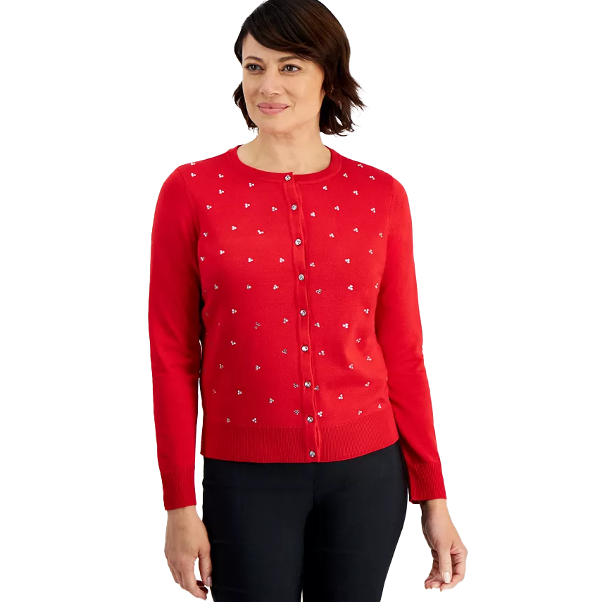 A woman is wearing a red cardigan with small white embellishments and black pants.