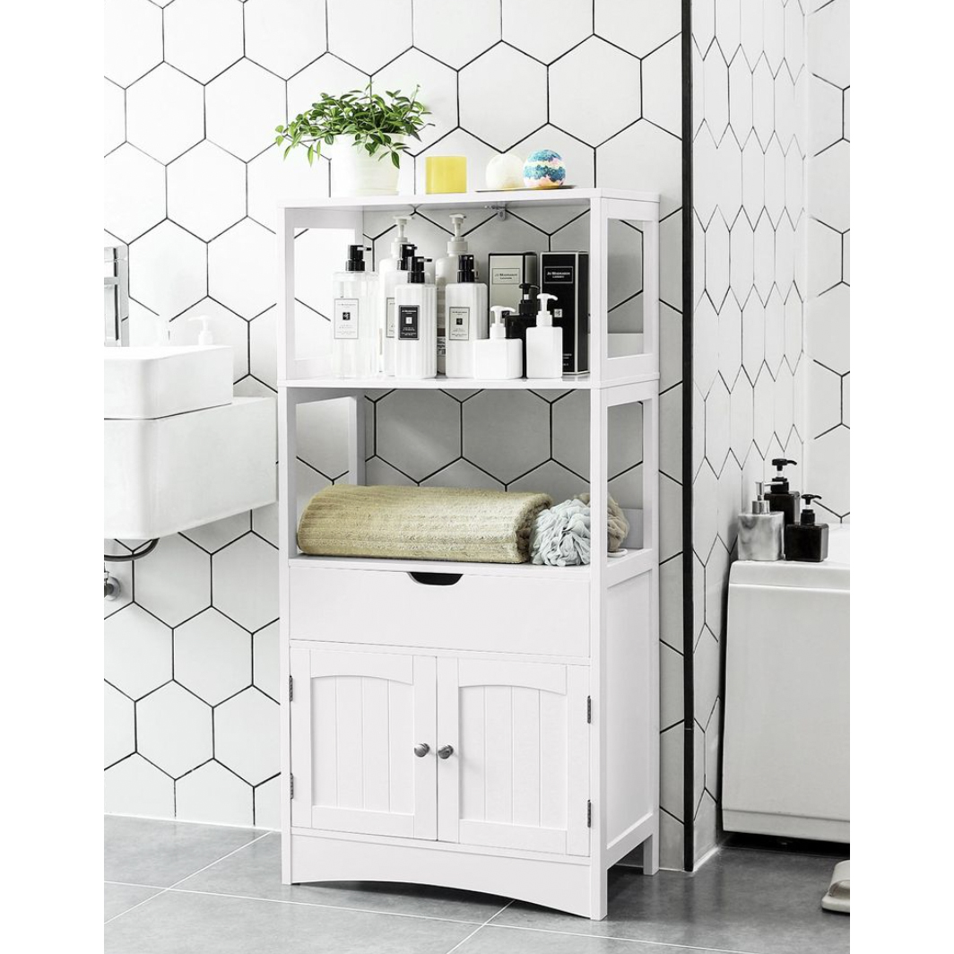 A white bathroom shelving unit with multiple levels holding towels, plants, and assorted toiletries.