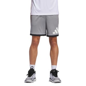Person wearing grey athletic shorts with a large logo on the left leg, white socks, black and grey sneakers, and a white top.
