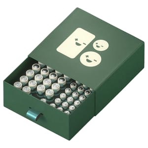 A green organizer case contains 46 cylindrical batteries with positive and negative symbols. The case has a pull-out design with a playful battery illustration on the lid.