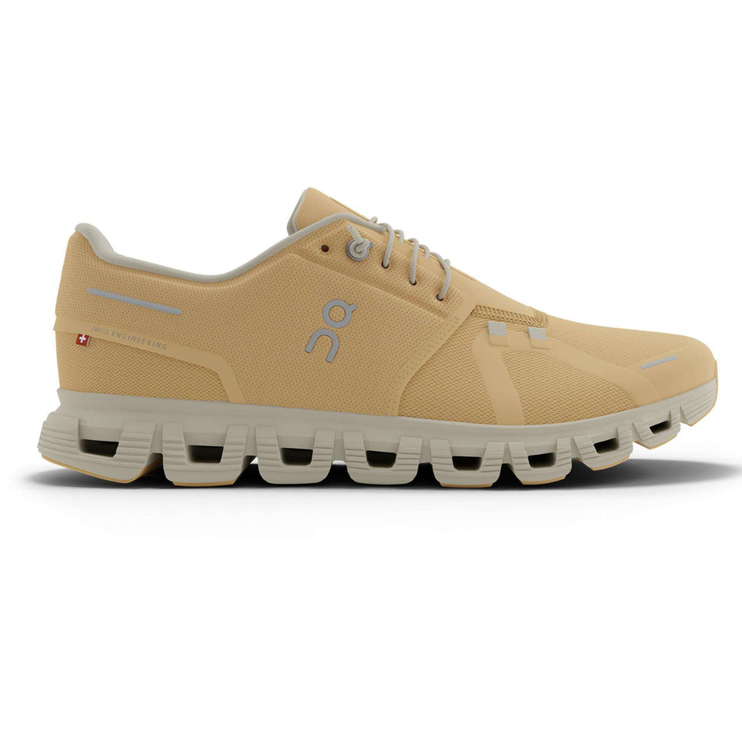 Beige athletic shoe with a unique sole design featuring hollow sections, showcasing a logo on the side and Swiss engineering text.
