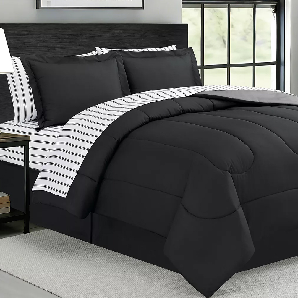 A modern bedding set featuring a black comforter with a subtle stitched design, paired with pillowcases and sheets in matching black and contrasting striped fabric.