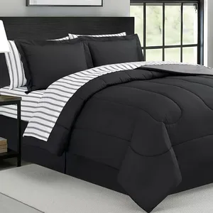 A modern bedding set featuring a black comforter with a subtle stitched design, paired with pillowcases and sheets in matching black and contrasting striped fabric.