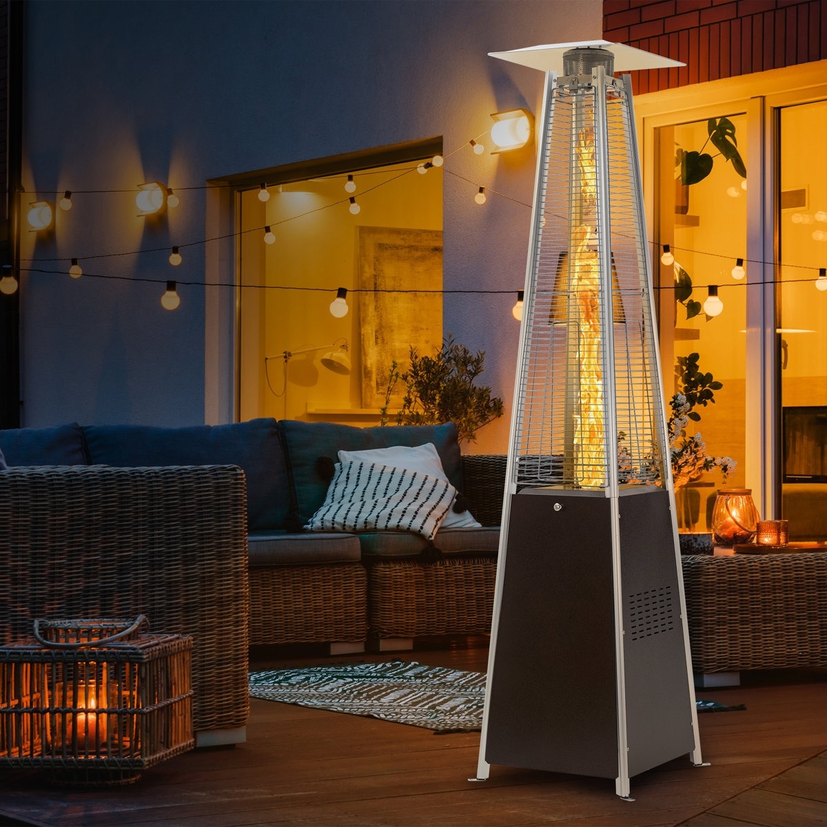 A pyramid-style outdoor patio heater is situated on a patio with wicker furniture and string lights.