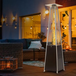 A pyramid-style outdoor patio heater is situated on a patio with wicker furniture and string lights.