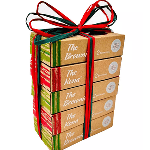 A gift pack with four stacked boxes of brownies, labeled \“The Brownie\“ and \“The Kona,\“ tied with red and green ribbons. Each box contains two brownies, branded with \“salt earth.\“