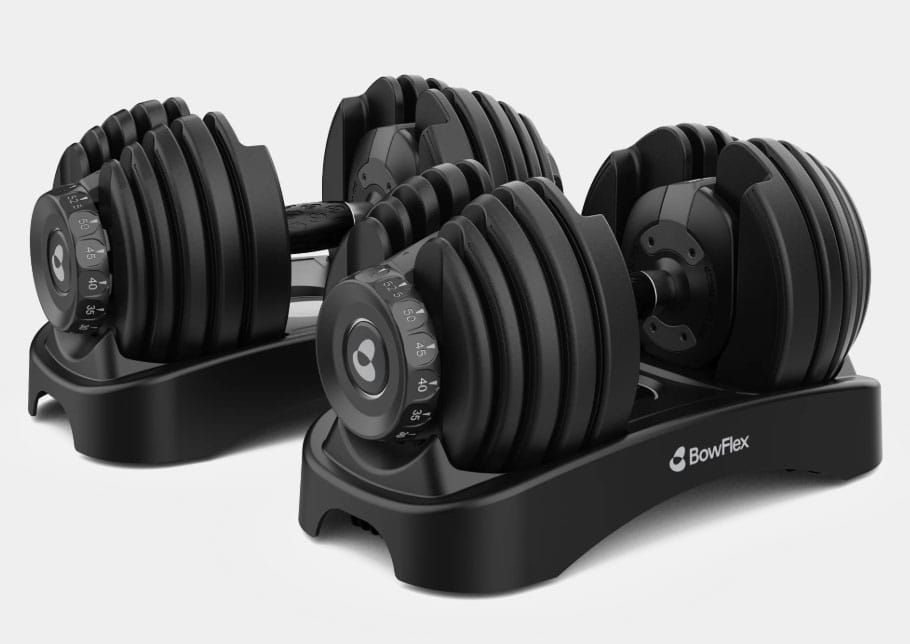 Two adjustable dumbbells with a black design, featuring weight selection dials and resting on a compact stand.