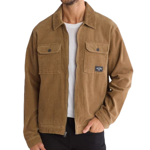 A man is wearing a brown corduroy jacket with a collared neckline, two chest pockets with button flaps, and a logo patch on the left pocket.