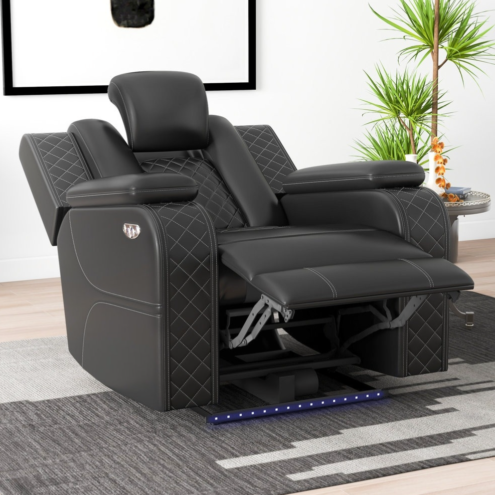 A black reclining chair with diamond-pattern stitching and an adjustable footrest is set on a modern rug, surrounded by a potted plant, a lamp, and a side table, creating a cozy living space.