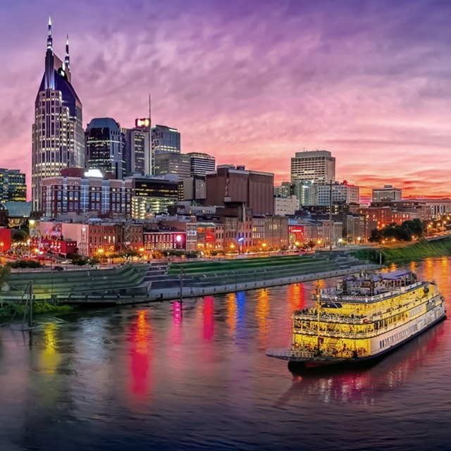 A vivid sunset over the Nashville skyline with a riverboat on the Cumberland River.