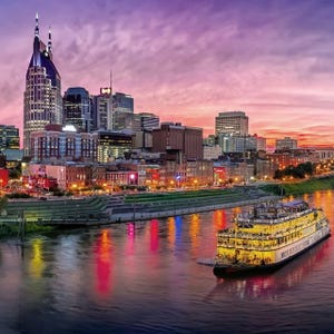 A vivid sunset over the Nashville skyline with a riverboat on the Cumberland River.