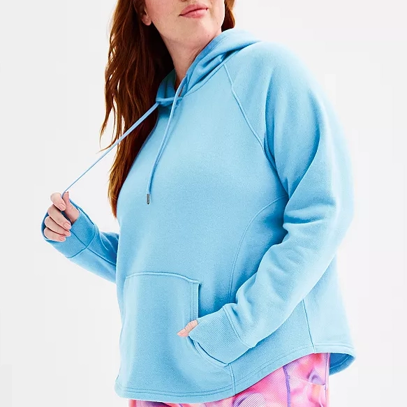 A woman wearing a light blue hoodie with a kangaroo pocket and drawstrings.