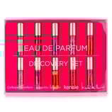 A set of six small cylindrical Eau de Parfum bottles by various designers displayed in pink packaging.