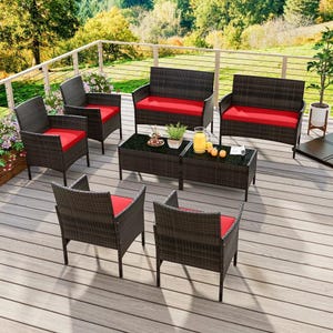 8-piece patio set with dark wicker frames and red cushions includes two loveseats, four single chairs, and two coffee tables on a wooden deck with a scenic background and floral accents.