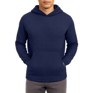 A man is wearing a navy blue, ribbed hooded sweatshirt with a front pouch pocket, paired with gray pants.