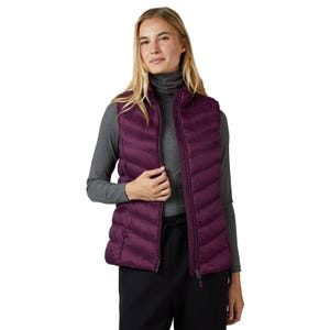 A woman wearing a purple quilted vest over a gray turtleneck and black pants.