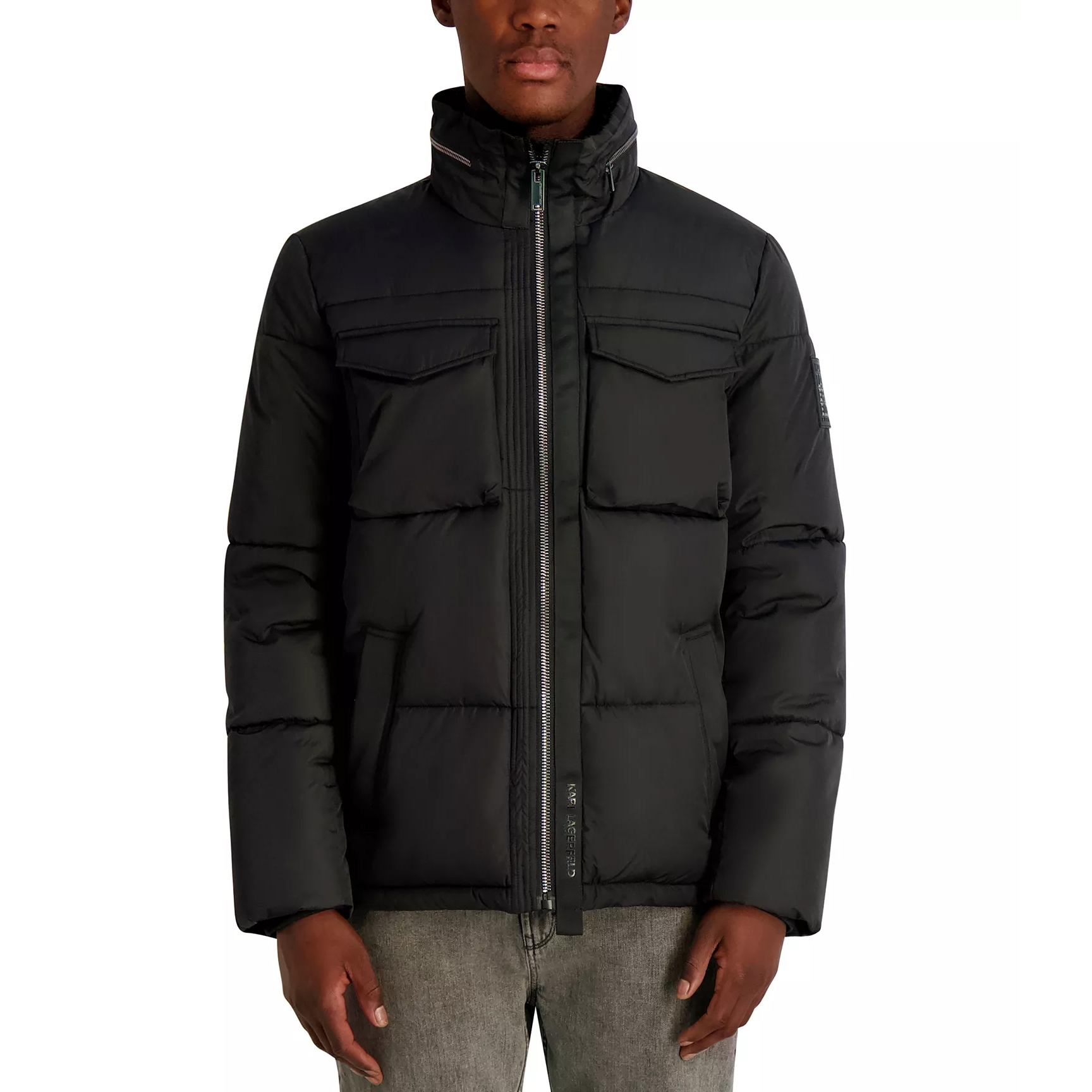 Black quilted down jacket with high collar, front zipper, chest pockets, and side pockets, paired with gray jeans.