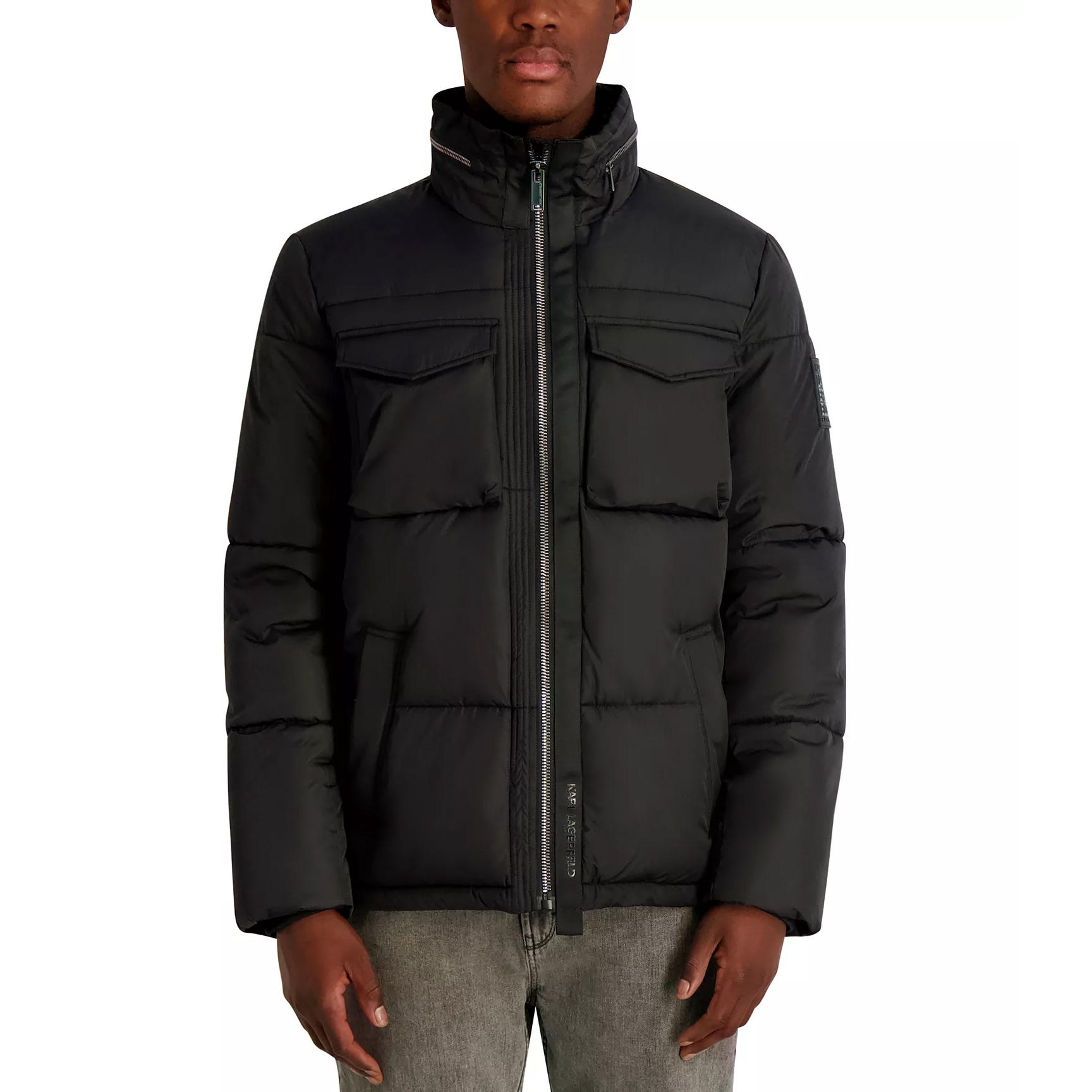 Black quilted down jacket with high collar, front zipper, chest pockets, and side pockets, paired with gray jeans.