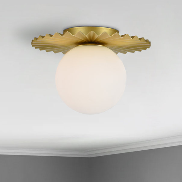 A ceiling-mounted light fixture with a frosted glass sphere and a ruffled golden base.