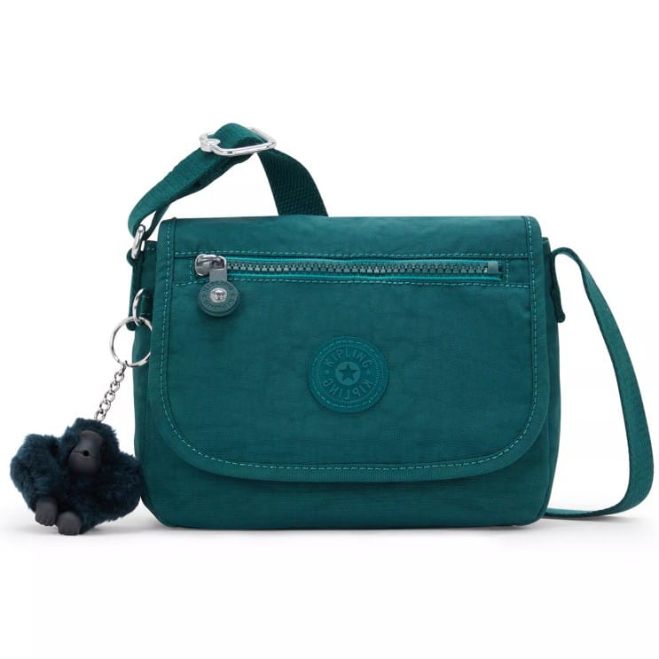 A teal crossbody bag with a front zip pocket, main flap, and a keychain featuring a small plush toy.