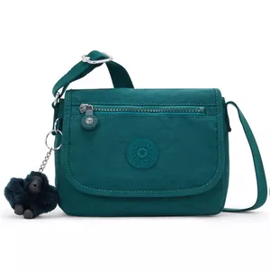 A teal crossbody bag with a front zip pocket, main flap, and a keychain featuring a small plush toy.