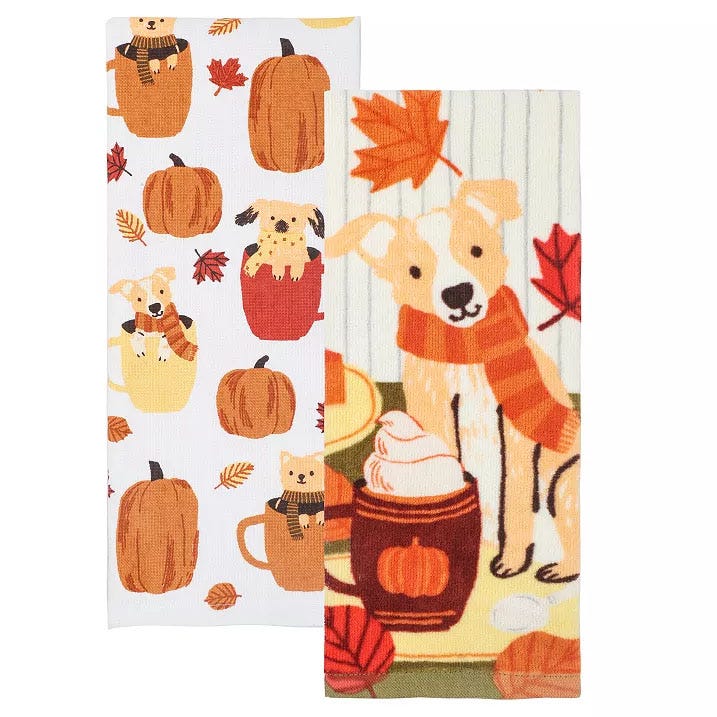 Two kitchen towels feature autumnal designs with pumpkins, leaves, and dogs; one towel showcases dogs in scarves amidst fall foliage, and the other displays puppies peeking out of pumpkins.