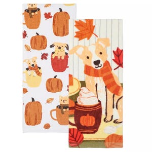 Two kitchen towels feature autumnal designs with pumpkins, leaves, and dogs; one towel showcases dogs in scarves amidst fall foliage, and the other displays puppies peeking out of pumpkins.