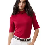 Woman in a red short-sleeve turtleneck top paired with white pants and a dark brown belt.