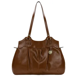 A brown leather handbag with double handles and a decorative metal charm. The design features pleats on the front and a small embossed logo in the corner.