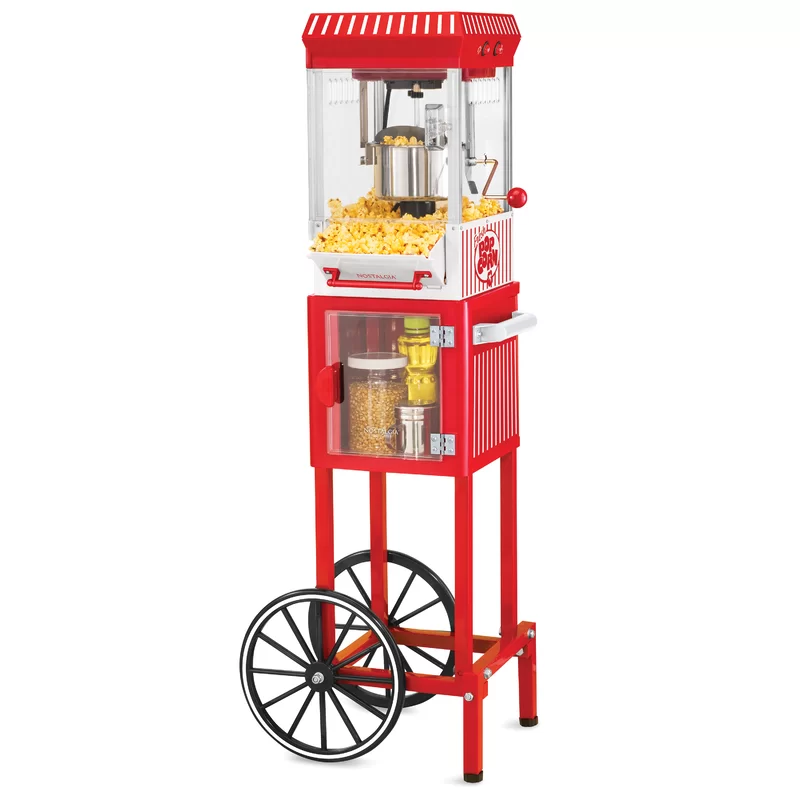The red popcorn maker and concession cart features a classic design, with a small glass cabinet and a storage area holding popcorn kernels and oil. It has two large wheels and a countertop-style popper on top, perfect for making popcorn.