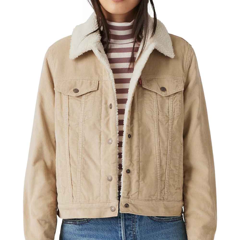 A beige corduroy jacket with a shearling collar is worn over a striped turtleneck top, paired with blue jeans.