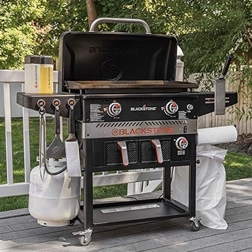 A Blackstone outdoor griddle with side shelves and a propane tank attached, set up on a patio.
