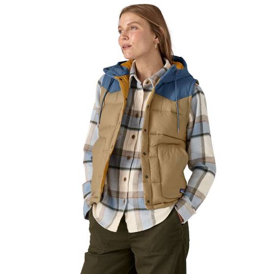 The Patagonia Bivvy Vest features a two-tone design with a blue hood, tan body, and large pockets. It's paired with a plaid shirt, offering a casual, layered look suitable for outdoor activities.
