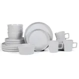 A set of white ceramic dishes including bowls, plates, and mugs with handles, displayed in a neat arrangement.