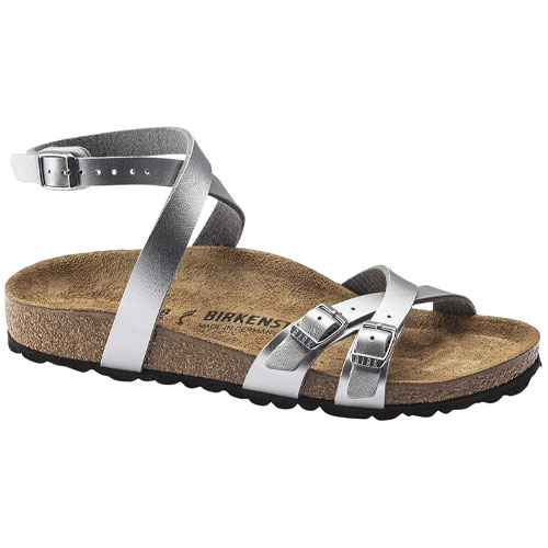 A silver strappy sandal with an adjustable ankle strap and two front buckle straps, featuring a cork footbed and black textured sole, branded with \“BIRKENSTOCK.\“