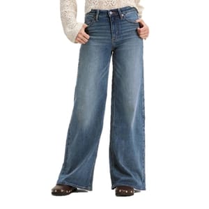 Wide-leg blue jeans paired with a lace long-sleeve top and brown shoes with metal studs.
