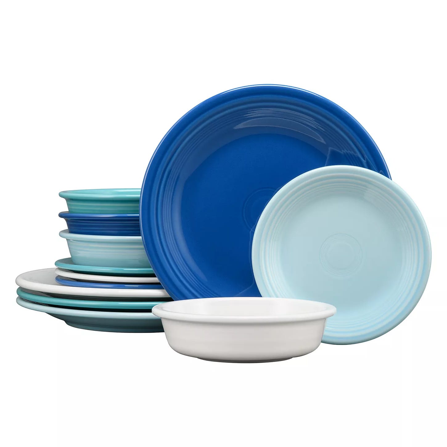 A collection of ceramic dinnerware in various shades of blue and white, including plates and bowls, featuring a simple, ridged design.