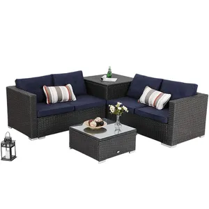 Outdoor sectional furniture set with dark wicker frame, navy cushions, and striped pillows includes a corner table with a glass top and a matching square coffee table. A decorative lantern and floral vase are on the tables.