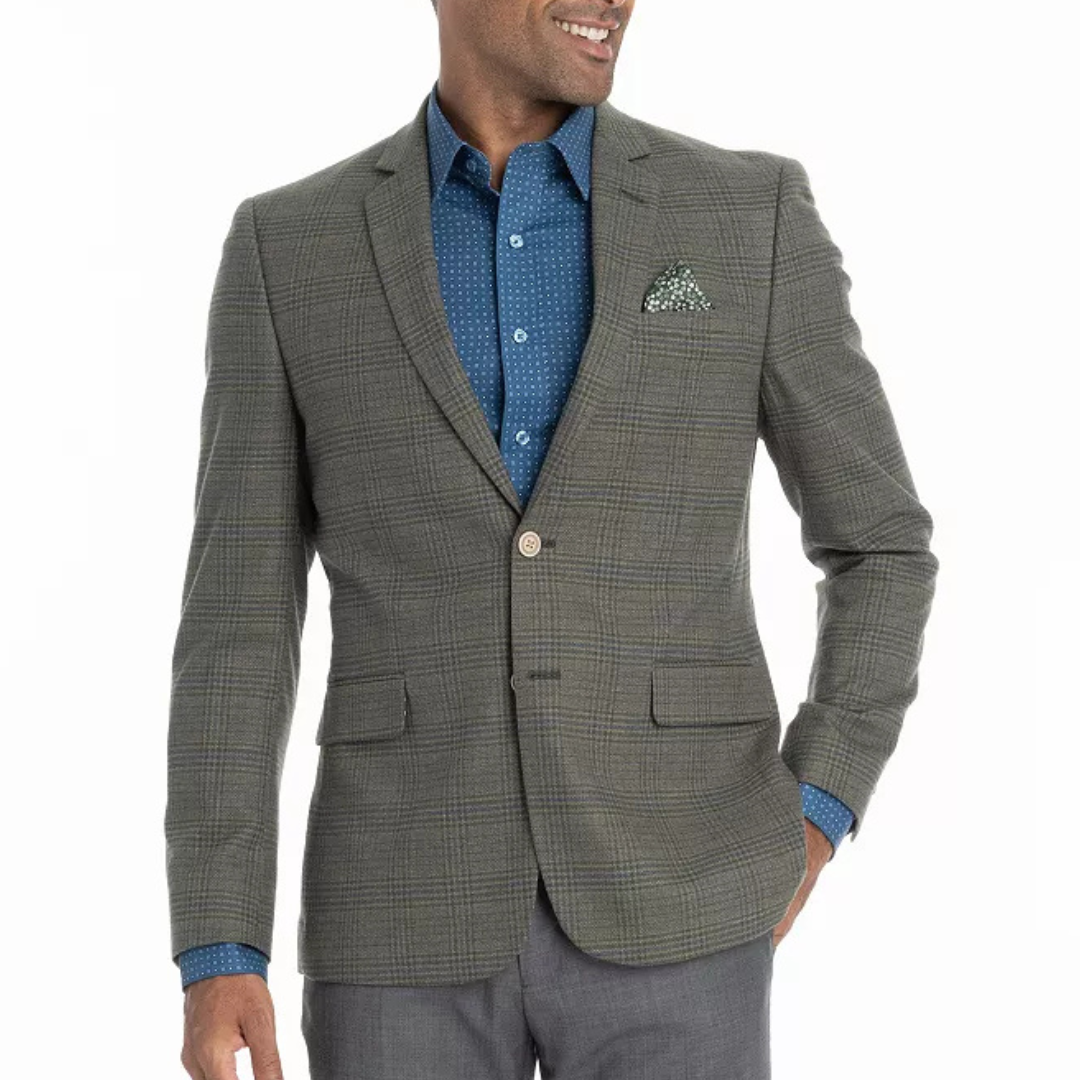 A man is wearing a plaid blazer with a blue patterned shirt and gray pants. A pocket square is tucked into the blazer's chest pocket.