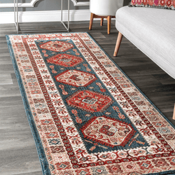 A decorative area rug with a traditional Persian-style pattern featuring blue, red, and cream colors, placed on a dark wood floor next to a gray sofa and white furniture.