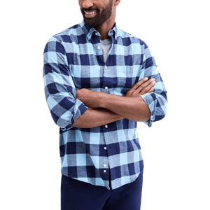 A man is wearing a blue checkered button-up shirt over a gray t-shirt, with the shirt sleeves rolled up.