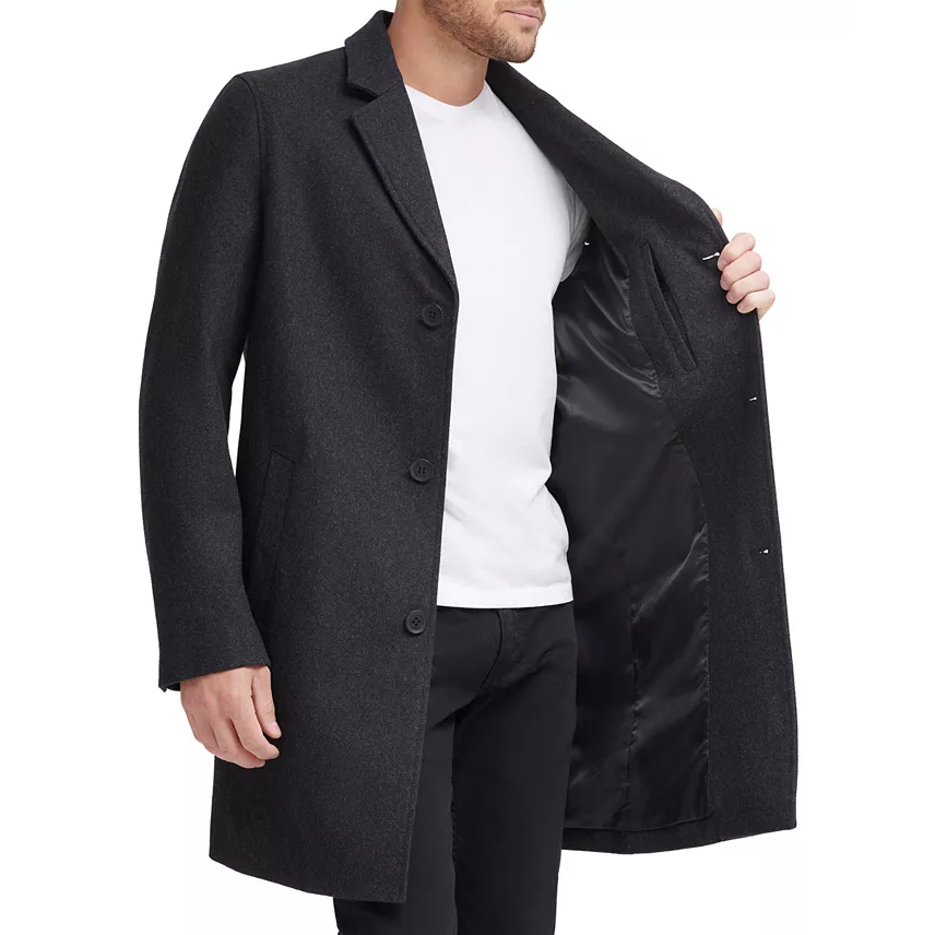 Cole Haan Melton Classic-Fit Topcoat is a charcoal, single-breasted coat with a smooth, black inner lining. It features three buttons and notched lapels, offering a sleek, timeless look.