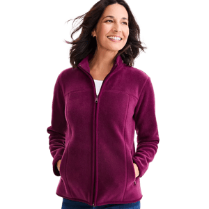 A woman is wearing a magenta fleece zip-up jacket with a high collar and pockets, paired with a white top and blue jeans.