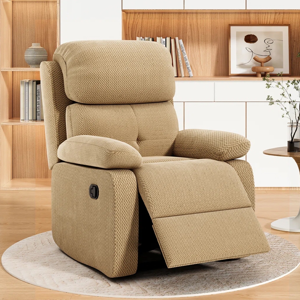 A beige recliner chair with a textured fabric finish is shown in a living room setting, featuring a manual lever for reclining.
