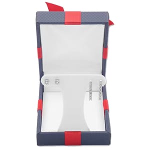 A pair of stud earrings and a pair of vertically aligned drop earrings with gemstones are displayed in an open navy and red jewelry box.